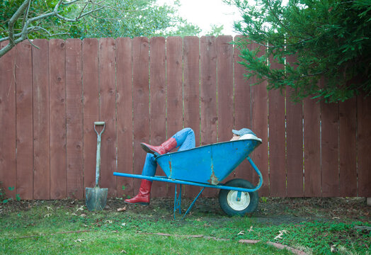 Girl resting in her blue wheelbarrow after working in the yard