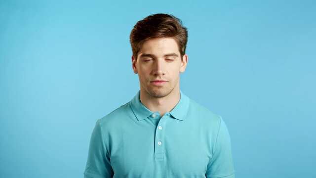 Portrait of handsome man in blue t-shirt looking to camera. Guy in studio on bright minimal background.