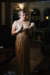 general plan a woman in a golden dress in the image of 20s looks at the camera