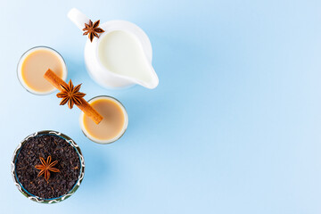 Tea with milk and spices on a blue background. Masala chai in turkish tea cups. Indian national drink and milk jug on a pastel background. Copy space. Top view