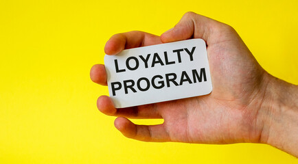 Loyalty program card in hand isolated on yellow background