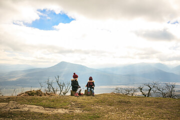 Fototapeta premium two little girls, sisters sit high in the mountains, playing palms and rock, scissors, paper. traveling with children. vacation in the winter.