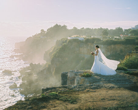 Bride standing on edge of rocky cliff