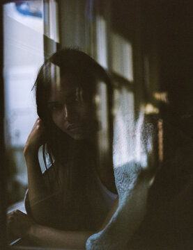 Looking at a beautiful woman behind window glass. On film.