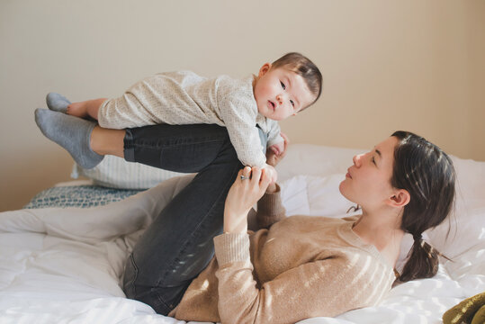 Baby flying like airplane on mom's legs