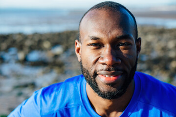 Close up portrait of an African fitness instructor outside on a beach, smiling