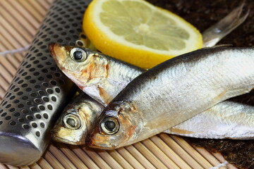 fresh sardines with knife and lemon on sushi mat