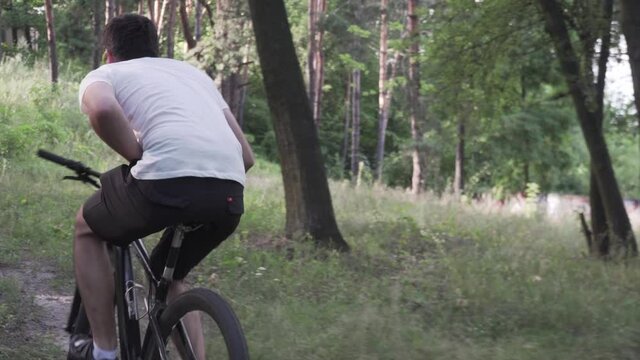 Caucasian man have stomach pain while cycling training in forest. Male cyclist diarrhea in park. Athlete looking for place to defify behind tree slacking off bike. Painful disease feeling unwell.