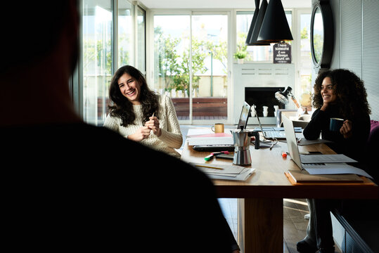 Smiling girls at desk during lunch break in office.