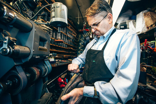 Cobbler cutting off excess shoe heel