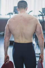 Obraz premium athlete with a wide muscular back goes with metal pancakes in the gym