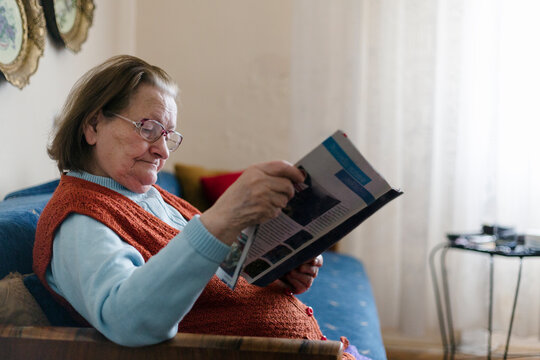 Senior woman sitting in her living room reading newspapers