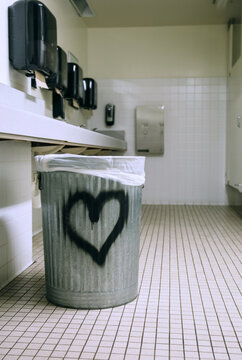 Gender neutral restroom with a heart spray painted on the trash can