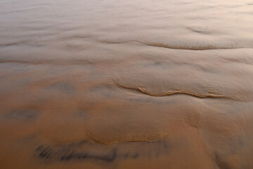 Waves pattern on sand beach. Close up to sand texture with wave marks on the beach