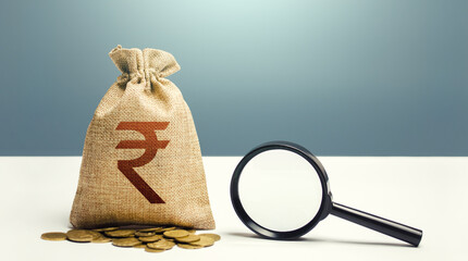 Indian rupee money bag and magnifying glass. Financial audit and monitoring of suspicious capital...