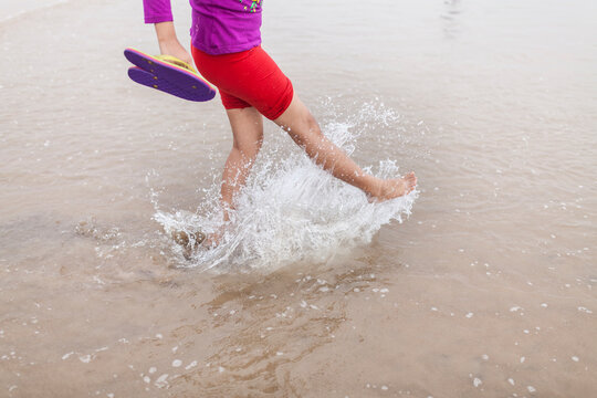 Teenage girl splashing water by foot in a sea beach
