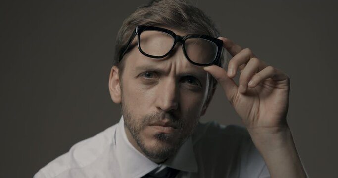 Man staring at camera and holding glasses