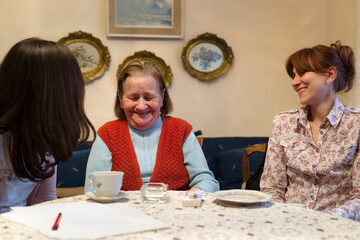 Granddaughter, her mum and grandma sitting and talking inside their home