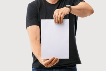 Man with blank paper sheet on grey background