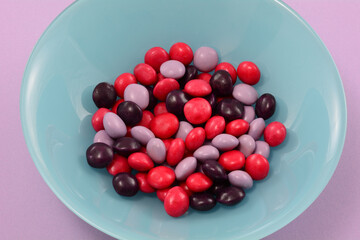 Strawberry, blackberry and raspberry fruit candies in blue bowl on lavender background