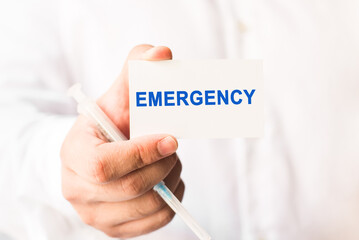 Word emergency on a white background with a syringe in hand. Medicine concept