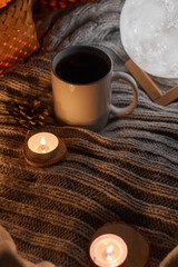 Cozy home with cup of coffee and a book on a knitted cozy fabric. Hygge style. Autumn or winter morning at home, vintage style, still life