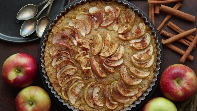Homemade Apple tart pie with fresh fruits and cinnamon sticks on rusty background