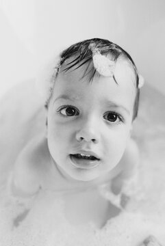 Black and white close up of a cute young boy taking a bath