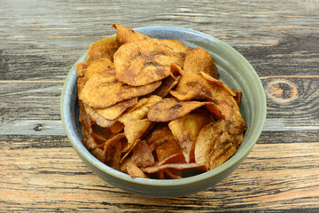 Sweet plantain chips side dish or snack in ceramic snack bowl on table 