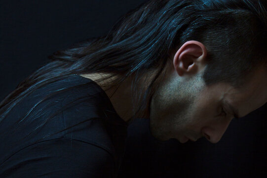 man bowing down in repentance on black background