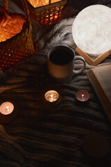 Cozy home with cup of coffee and a book on a knitted cozy fabric. Hygge style. Autumn or winter morning at home, vintage style, still life