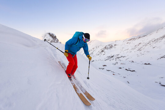 Man skiing downhill a steep slope during sunset