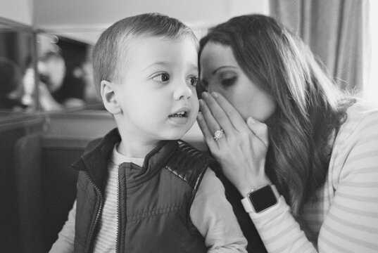 Mother whispering into her son's ear