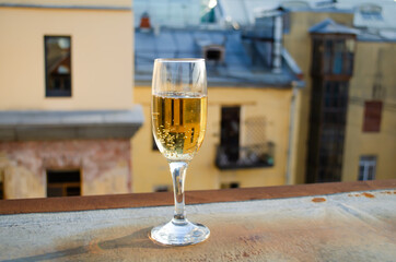 A glass of champagne on the background of city houses during sunset.