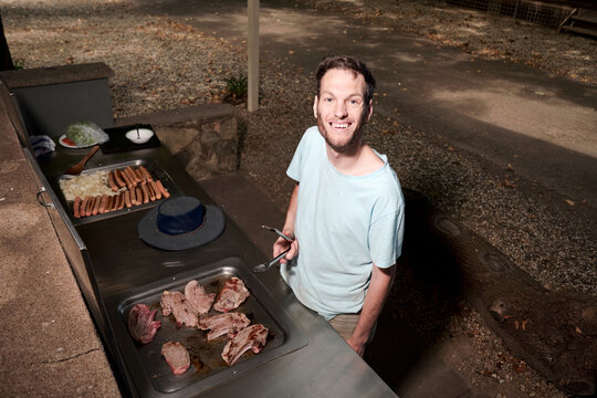 Man Looking up at Camera while Cooking on a Barbeque