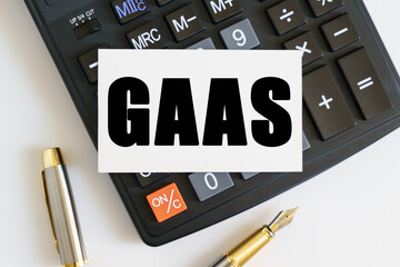 On the table there is a pen, a calculator and a business card on which the text is written GAAS. GENERALLY ACCEPTED AUDIT STANDARDS