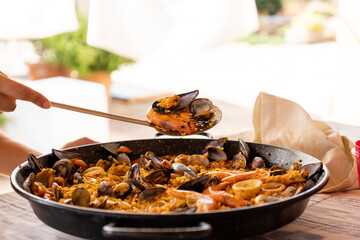 Serving homemade seafood paella with prawns and mussels on the spatula