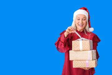 Elderly woman with Christmas gifts on color background