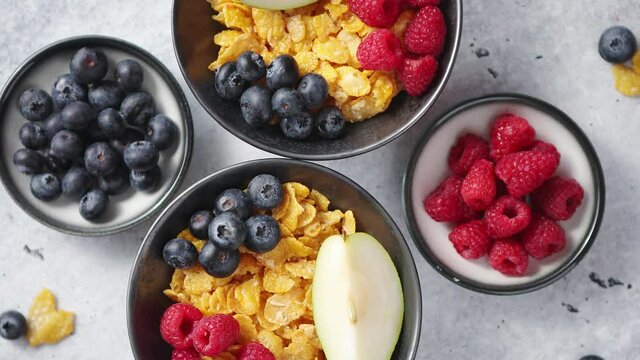 Golden cornflakes with fresh fruits of raspberries, blueberries and pear in ceramic bowl
