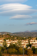 Large lenticular clouds over the roofs of residential houses in a housing estate at sunset
