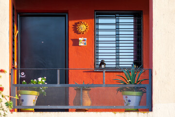 Fototapeta na wymiar Colorful exterior entrance of a house with orange wall, various decorations and potted plants