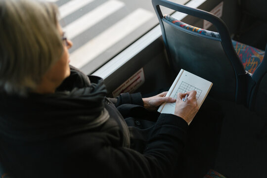 Mature caucasian woman playing sudoku on bus ride