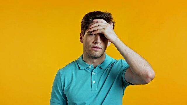 Portrait of young man doing facepalm gesture, like no, I forgot. Unhappy guy feeling sorrow, regret, drama, failure. He isolated on yellow wall