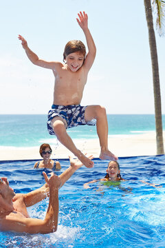 Kids playing in pool with their parents on vacation
