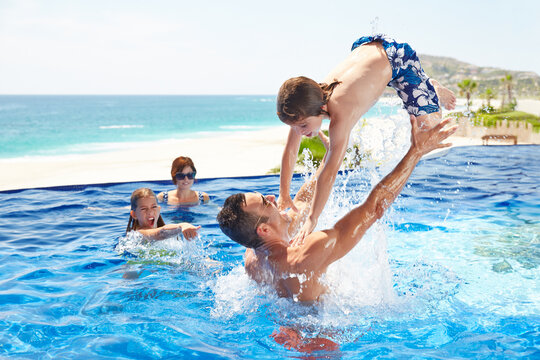 Kids playing in pool with their parents on vacation