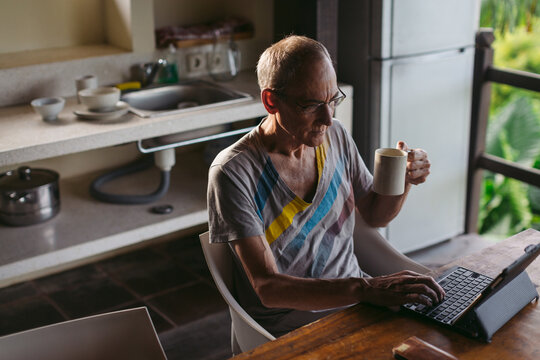 Mature man in his 60's working and traveling with tablet in trop