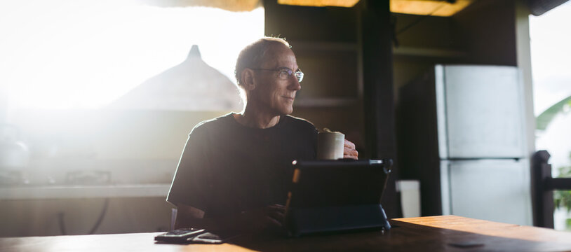 Mature man in his 60's working and traveling with tablet in trop