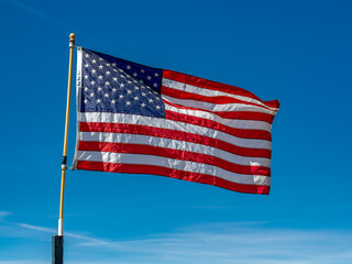 USA Flag waving against a bright blue sky.