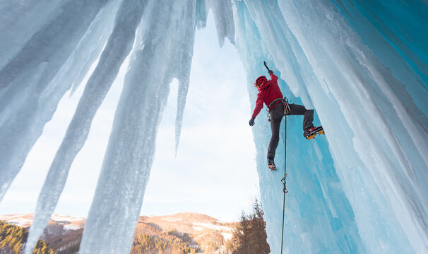 Female ice climber admiring hanging on ice axe
