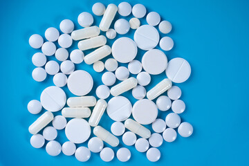 Tablets and pills top view. Tablets of different shapes and sizes on blue background. Concept pharmacology. Medicines symbolize pharmaceutical industry. Drug production. Pharmacology preparations.